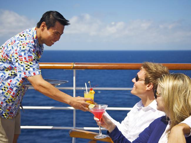Pareja recibiendo cocteles en un crucero de uno de los trabajadores de la embarcación (Getty Images)