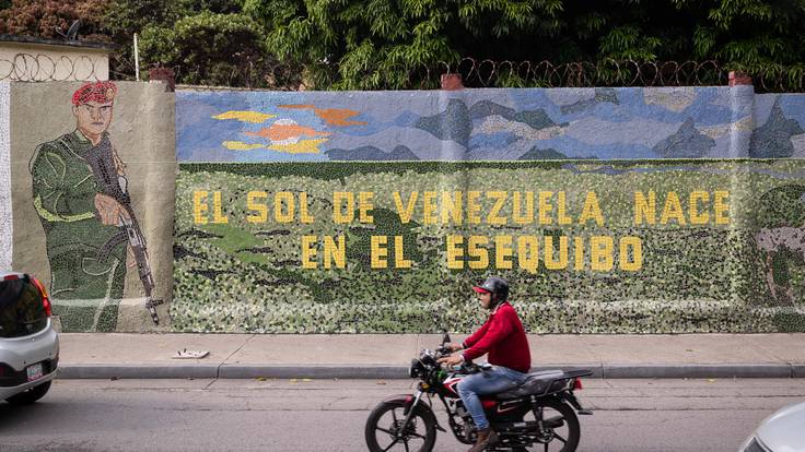 AME3693. CARACAS (VENEZUELA), 03/11/2023.- Un hombre conduce una moto frente a un mural que dice &quot;El sol de Venezuela nace por el esequibo&quot;, el 2 de noviembre de 2023, en Caracas (Venezuela). Venezuela celebrará dentro de un mes un referendo consultivo con el que espera aprobar, sin carácter vinculante, la anexión de la Guayana Esequiba, un territorio de casi 160.000 kilómetros cuadrados en disputa con Guyana, al mapa del país, un movimiento unilateral que representa la mayor apuesta de Caracas en esta controversia de más de un siglo. EFE/ Rayner Peña R.