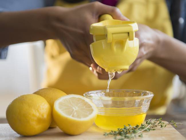 Mujer exprimiendo limones amarillos / Foto: GettyImages