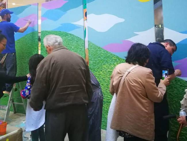 La gente del común también ayudan en la elaboración del mural. 
