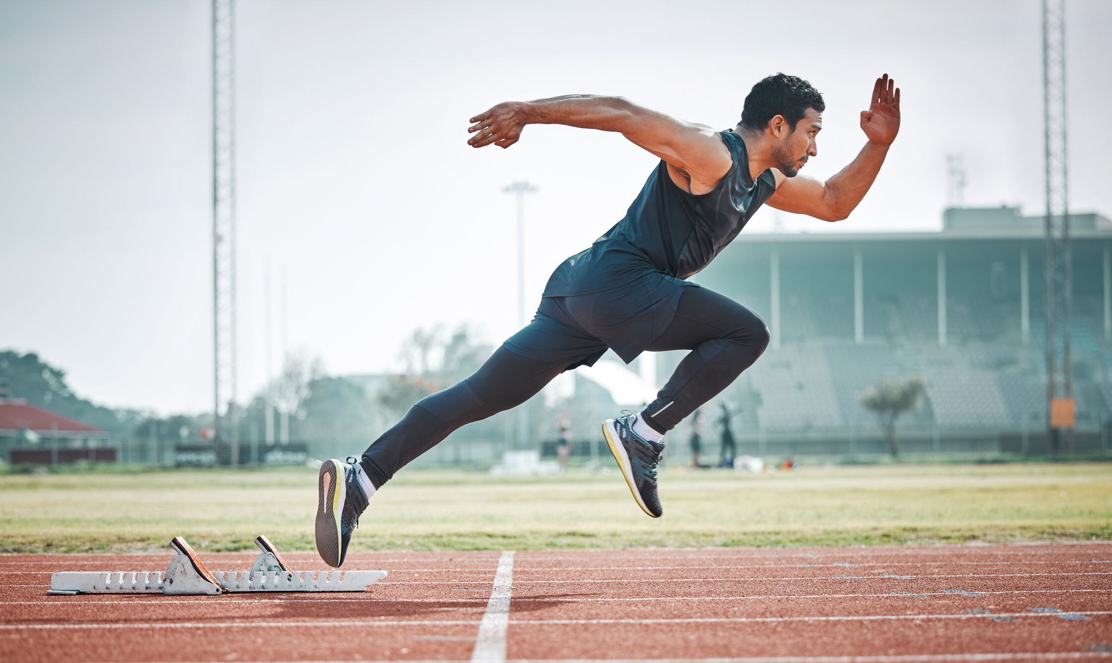 Joven atleta masculino corriendo en una pista al aire libre (Getty Images)