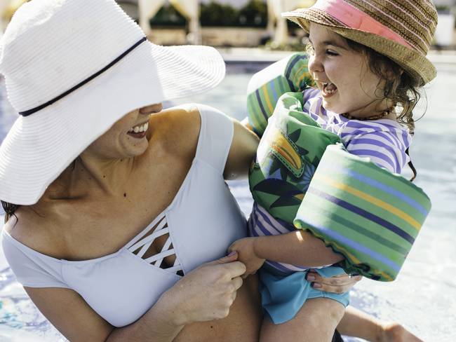 Madre e hija jugando y riendo en una piscina y disfrutande de sus vacaciones. (Foto vía Getty Images)