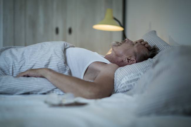 Hombre acostado en la cama preocupado (Getty Images)