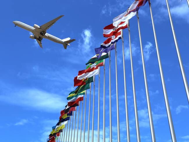 Avión volando sobre banderas de diferentes países / Foto: GettyImages