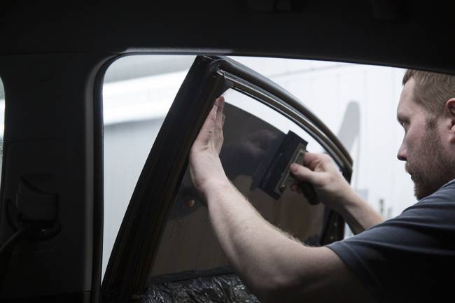 Hombre colocando película polarizada en vidrio de carro (Getty Images)