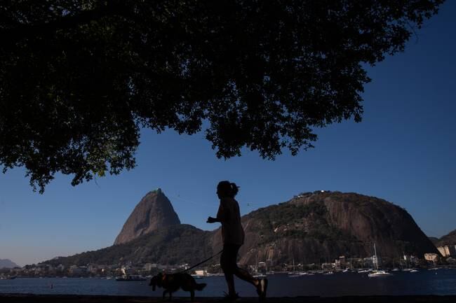 AME7503. RÍO DE JANEIRO (BRASIL), 02/08/2023.- Una mujer trota hoy con su perro por Botafogo, con las montañas del Pan de Azúcar al fondo, en Río de Janeiro (Brasil). EFE/André Coelho