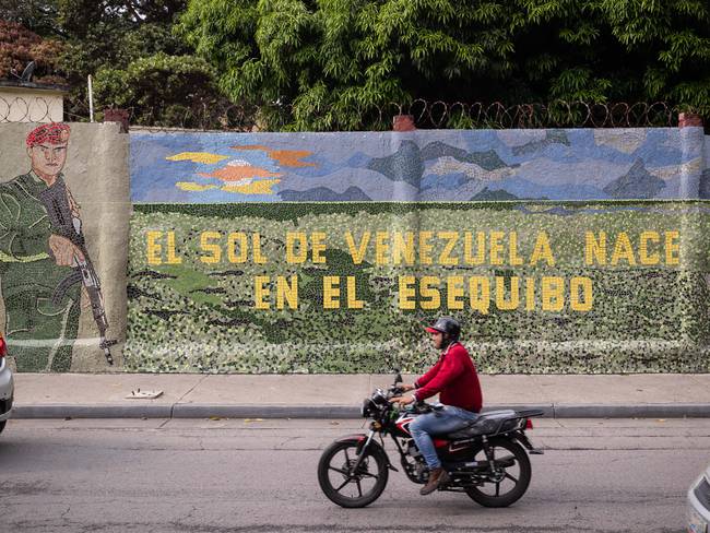 AME3693. CARACAS (VENEZUELA), 03/11/2023.- Un hombre conduce una moto frente a un mural que dice &quot;El sol de Venezuela nace por el esequibo&quot;, el 2 de noviembre de 2023, en Caracas (Venezuela). Venezuela celebrará dentro de un mes un referendo consultivo con el que espera aprobar, sin carácter vinculante, la anexión de la Guayana Esequiba, un territorio de casi 160.000 kilómetros cuadrados en disputa con Guyana, al mapa del país, un movimiento unilateral que representa la mayor apuesta de Caracas en esta controversia de más de un siglo. EFE/ Rayner Peña R.