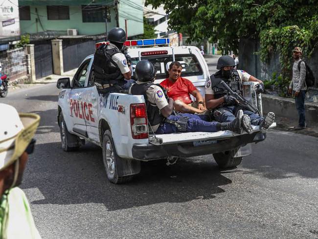 Una patrulla transporta a dos extranjeros golpeados por una turba que los acusó de portar cargadores de fusil y de hacer parte del comando que asesinó al presidente.