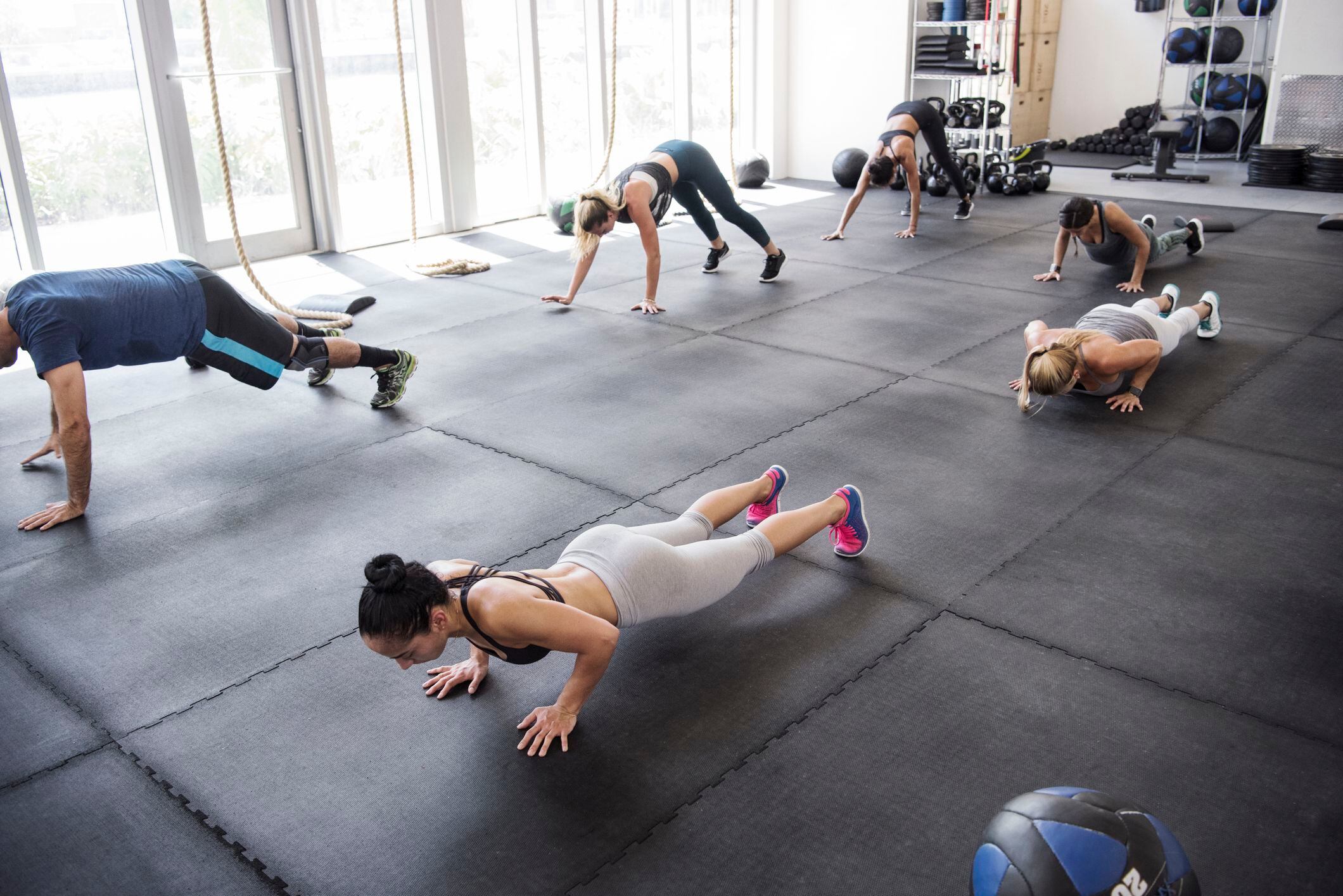 Personas realizando flexiones conjuntamente en el gimnasio (Getty Images)