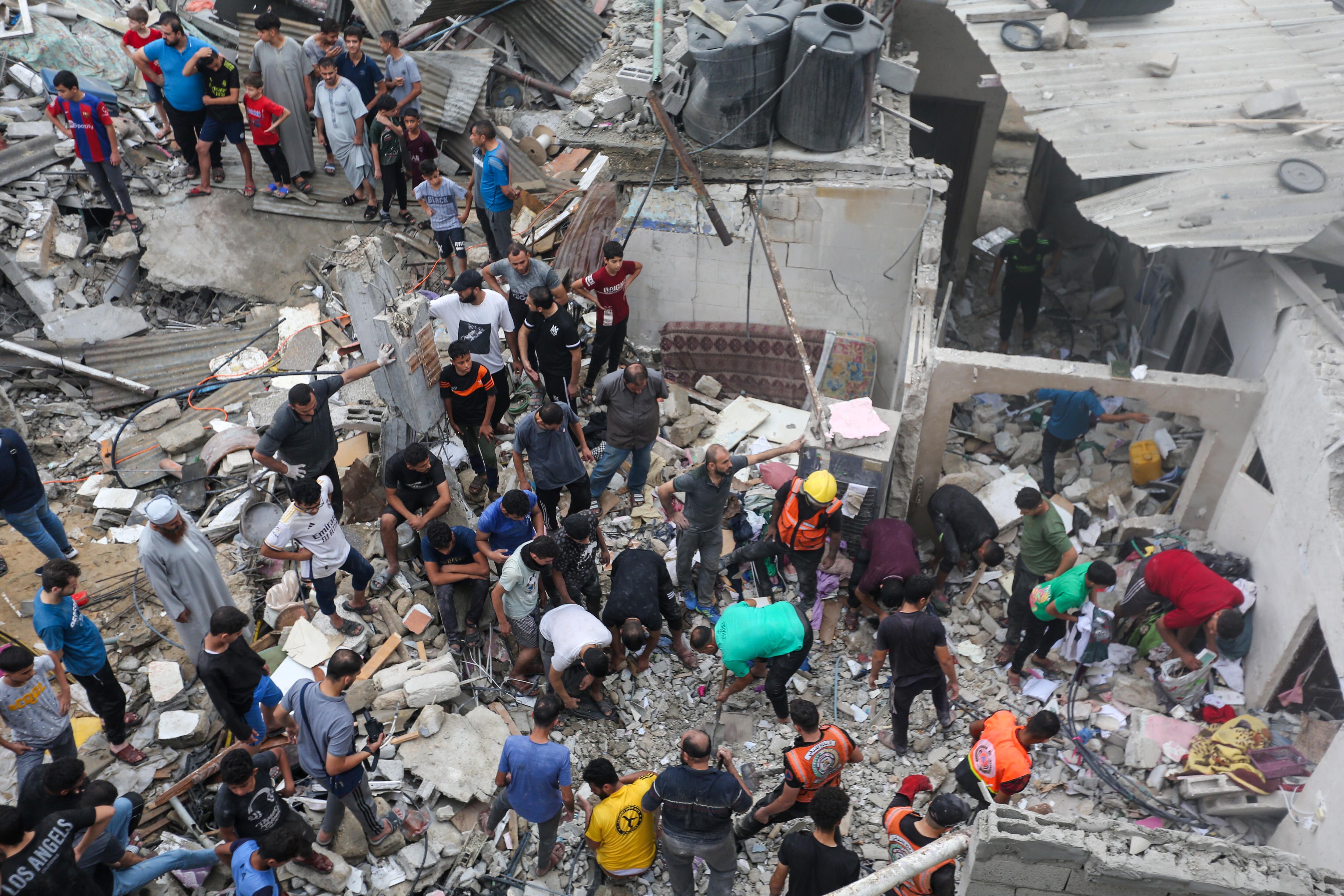 KHAN YUNIS, GAZA - OCTOBER 29: People search through buildings that were destroyed during Israeli air raids in the southern Gaza Strip on October 29, 2023 in Khan Yunis, Gaza. Heading into a third week of heavy bombing from Israel, Gaza buckles under a shortage of basic needs including fuel, whilst several neighborhoods on the Gaza strip have been wiped out and thousands have died and hundreds of thousands have been displaced. On October 7, Hamas launched a deadly attack in southern Israel that sparked a retaliatory siege of Gaza. (Photo by Ahmad Hasaballah/Getty Images)