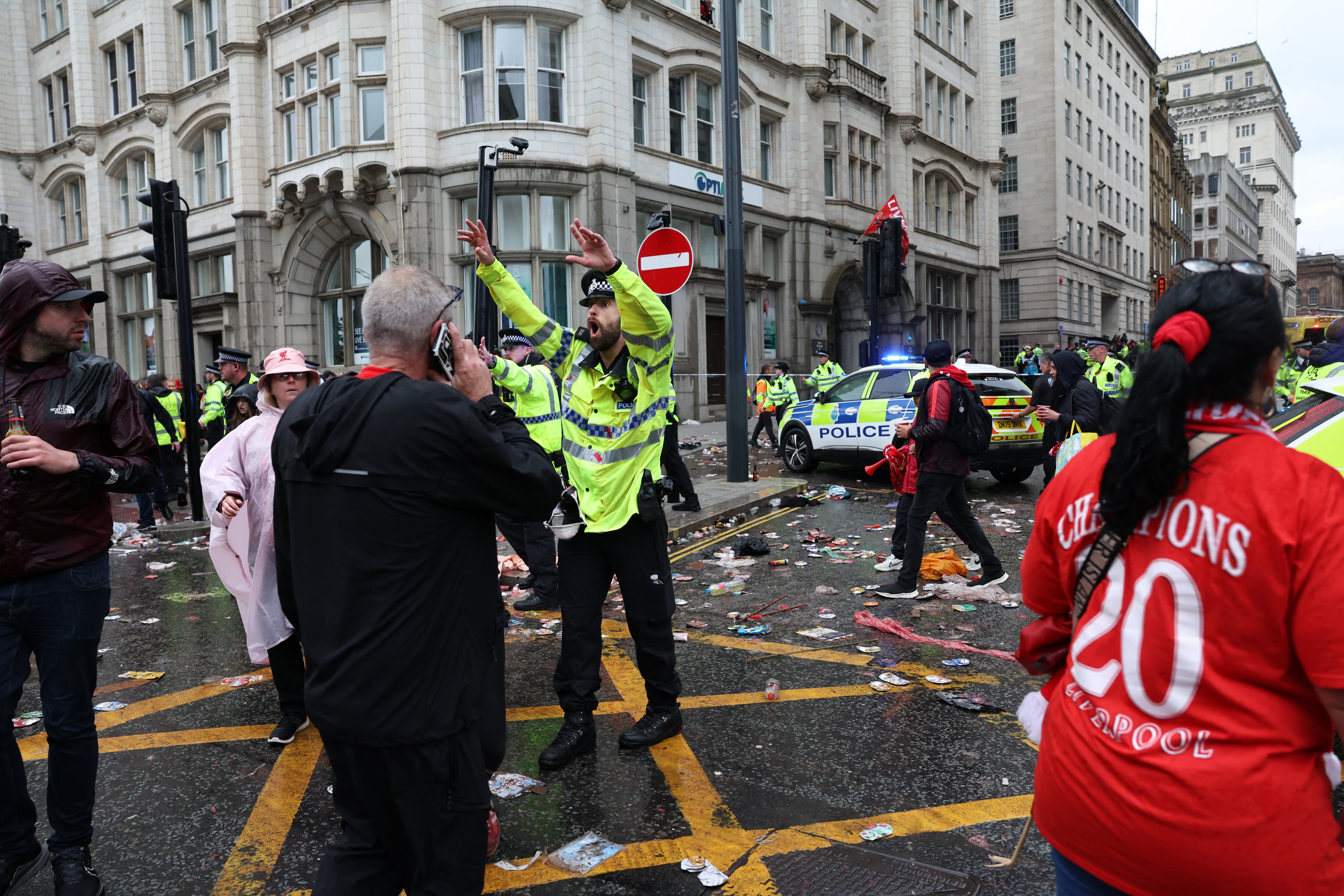 TOPSHOT - A Police officer shouts at Liverpool fans as he stands on duty a t a Police cordon at the entrance to Water Street, at the scene of an incident, on the sidelines of an open-top bus victory parade for Liverpool's Premier League title win, in Liverpool, north-west England on May 26, 2025. (Photo by Darren Staples / AFP) (Photo by DARREN STAPLES/AFP via Getty Images)          