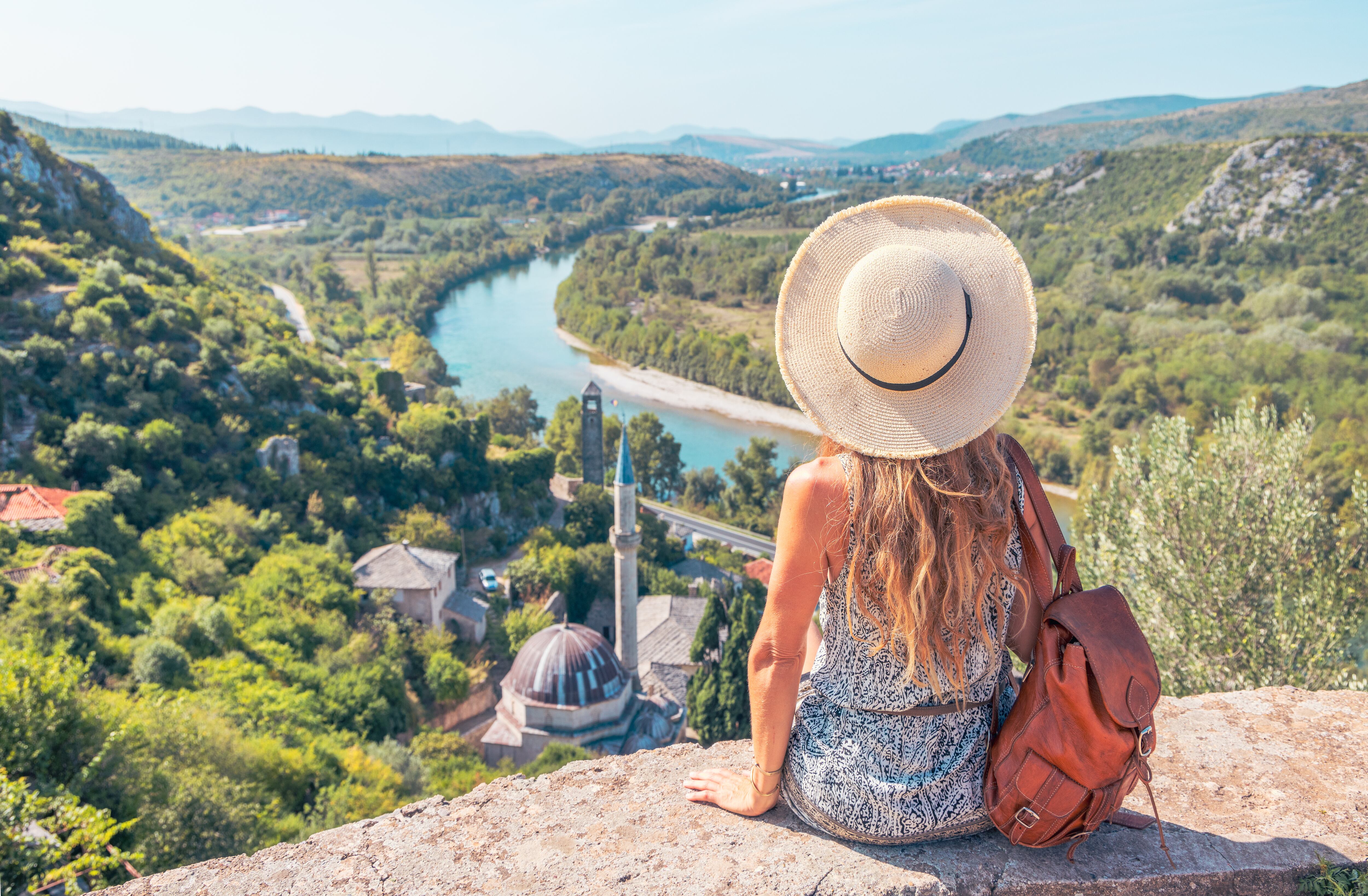 Mujer sentada admirando un paisaje montañoso (Foto vía GettyImages)