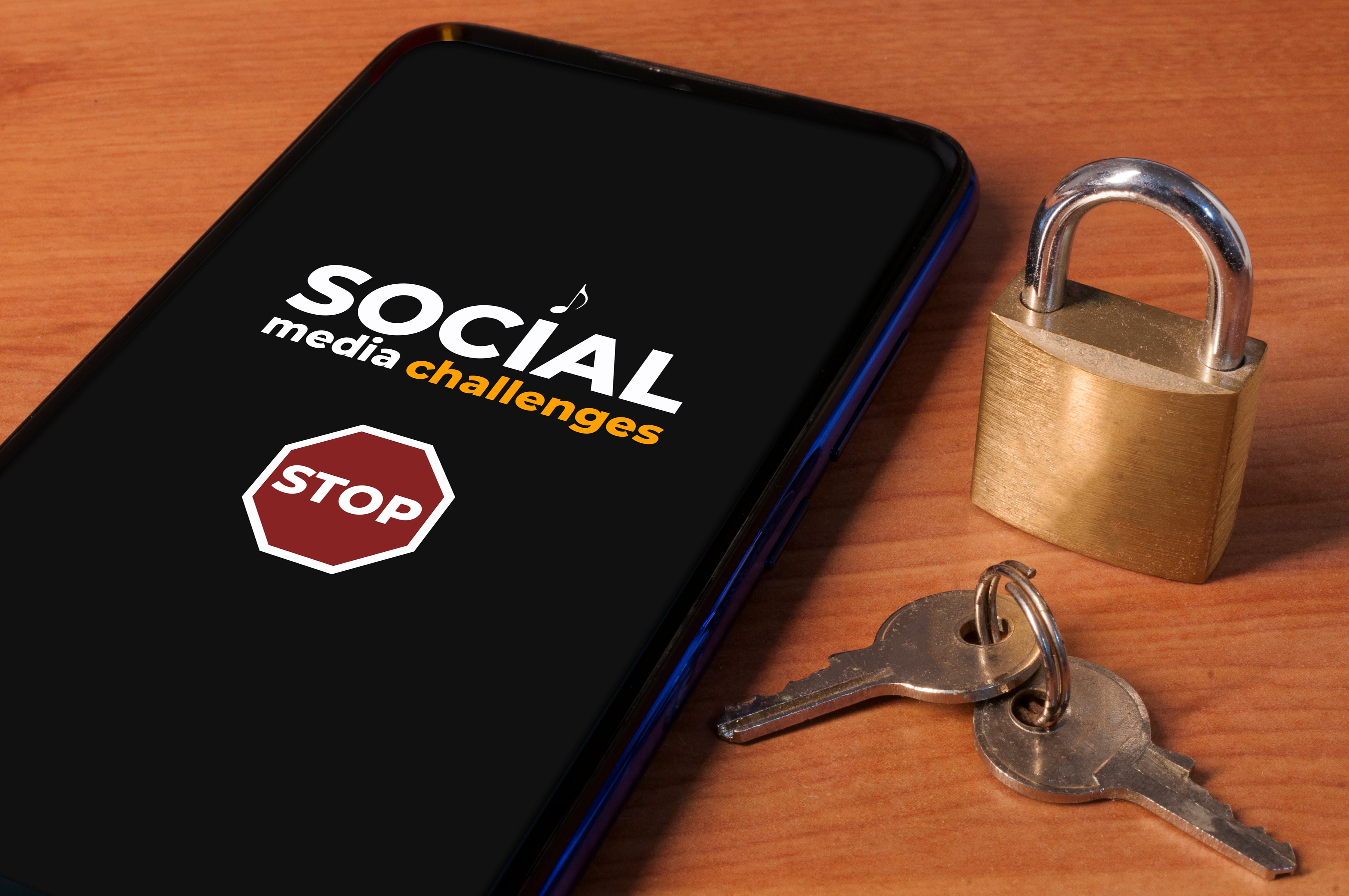 Smartphone showing the message "stop social media challenges" a wooden table with a lock and keys. Imagen tomada de Getty Imagenes (Crédito: Cristian Storto Fotografia)
