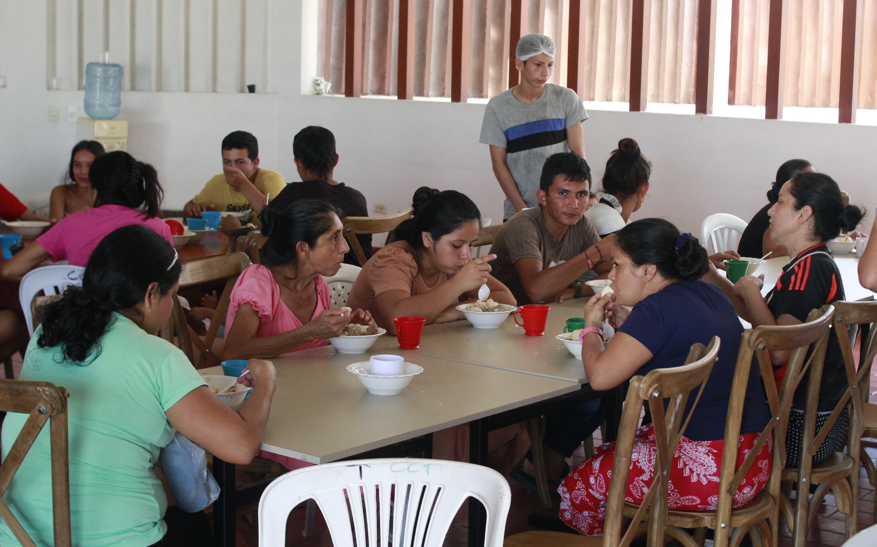AME3405. TIBÚ (COLOMBIA), 22/01/2025.- Personas comen en el Albergue del Seminario Menor en Tibú este miércoles, en Tibú (Colombia). Las calles de Tibú, un pueblo petrolero del departamento colombiano de Norte de Santander, han vuelto a ser escenario del éxodo de miles de personas que buscan refugiarse de la violencia entre la guerrilla del Ejército de Liberación Nacional (ELN) y una de las disidencias de la FARC. EFE/ Mario Caicedo