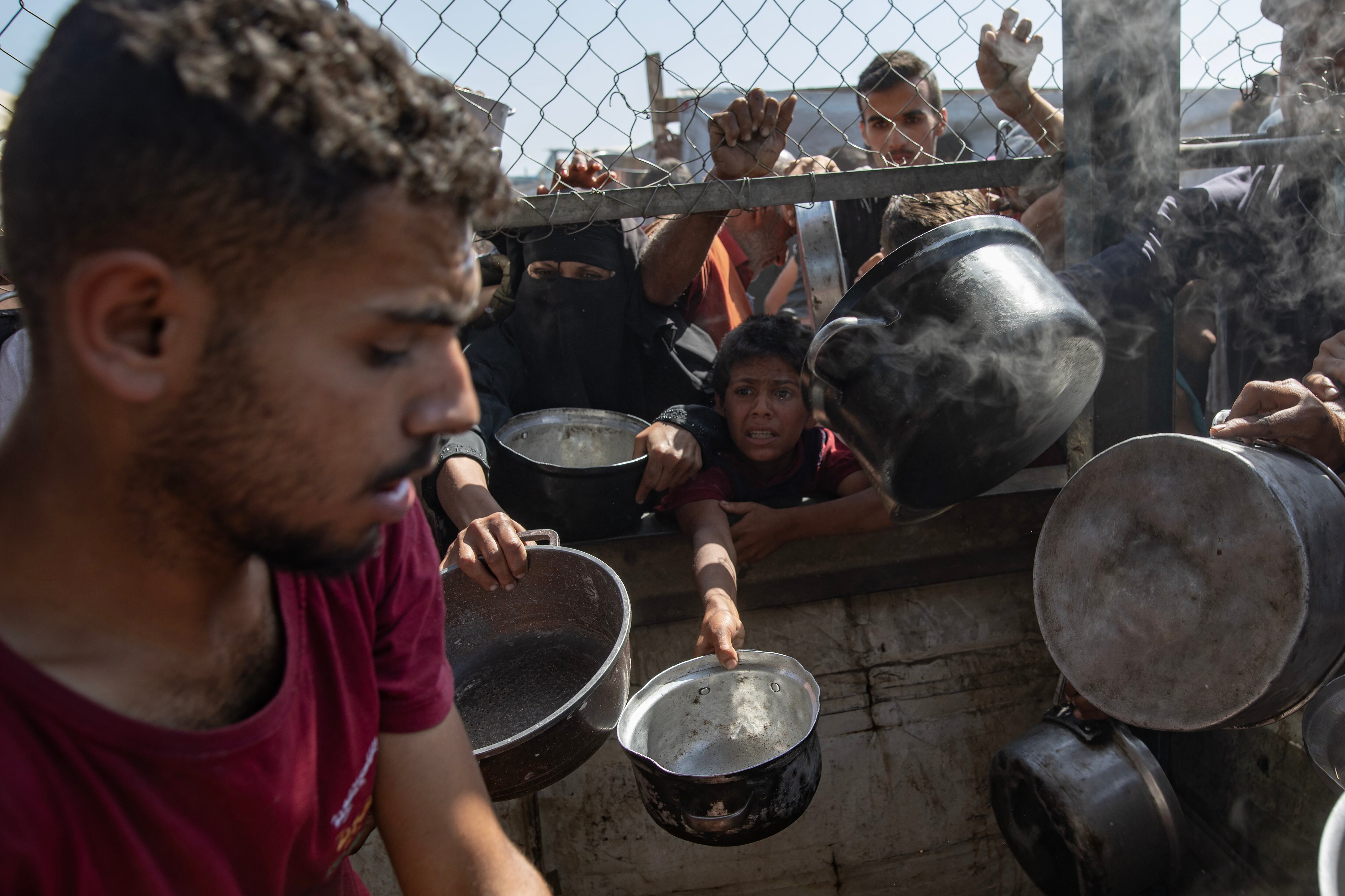 GAZA (-), 30/05/2025.- Internally displaced Palestinians gather outside a charity kitchen to receive limited rations amid a shortage of food, in Khan Younis, southern Gaza Strip, 30 May 2025. The United Nations has warned that "the entire population of Gaza is facing the risk of famine" since Israel closed border crossings on 02 March 2025, preventing the entry of essential supplies. The Gaza Government Media Office reported on 24 May that at least 58 people died due to malnutrition, and nearly 250 others due to a lack of food and medicine. EFE/EPA/HAITHAM IMAD