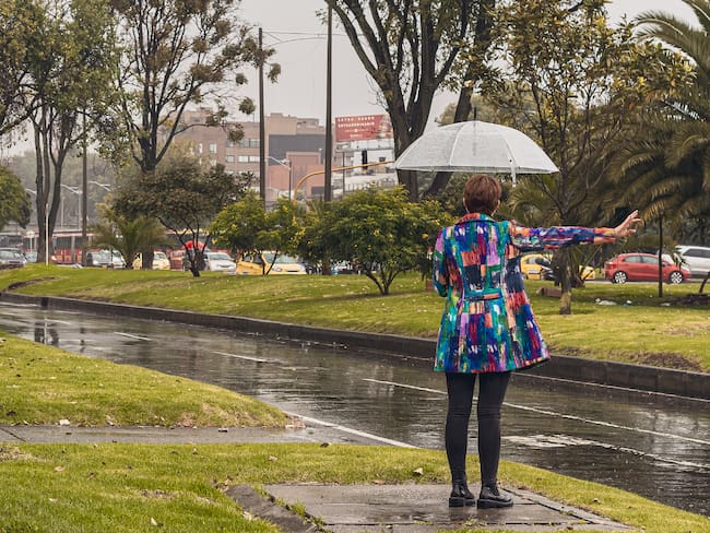 Mujer bajo la lluvia esperando el transporte público (Foto vía Getty Images)