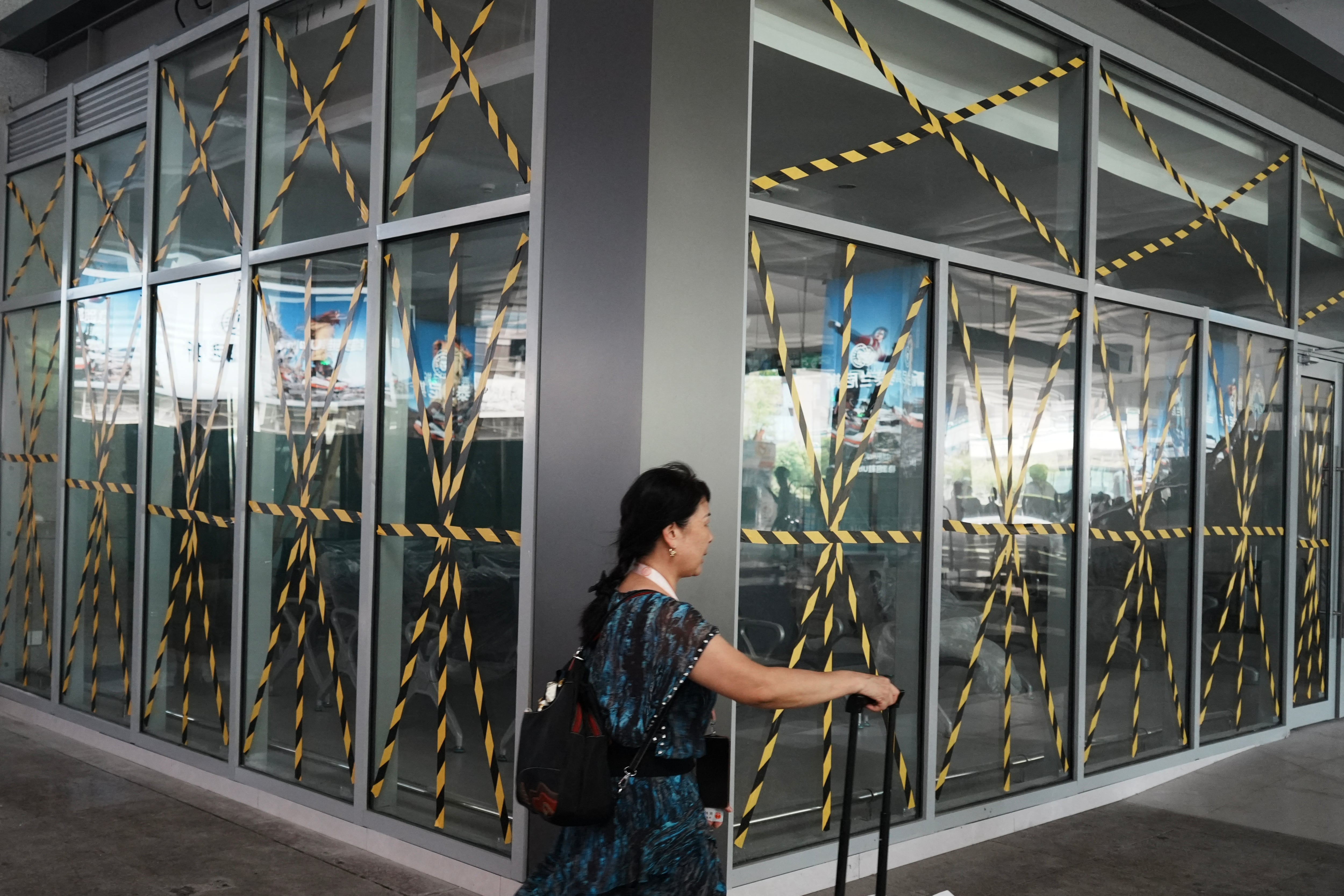A passenger walks past glass windows taped at a temporary waiting room at Hangzhou railway station in eastern China's Zhejiang province on August 9, 2026, as a precaution against Typhoon Dolphin. (Photo by CN-STR / AFP) / China OUT