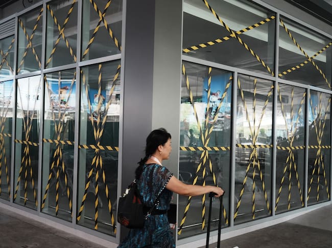 A passenger walks past glass windows taped at a temporary waiting room at Hangzhou railway station in eastern China's Zhejiang province on August 9, 2026, as a precaution against Typhoon Dolphin. (Photo by CN-STR / AFP) / China OUT