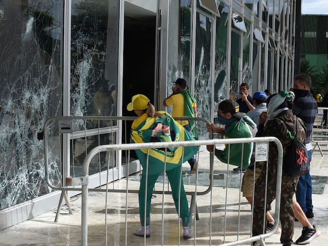Partidarios del expresidente brasileño Jair Bolsonaro destruyen una ventana del pleno de la Corte Suprema en Brasilia el 8 de enero de 2023. Foto de TON MOLINA/AFP vía Getty Images.