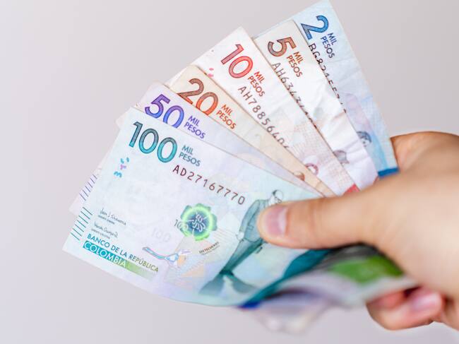 Persona sosteniendo varios billetes colombianos (Getty Images)