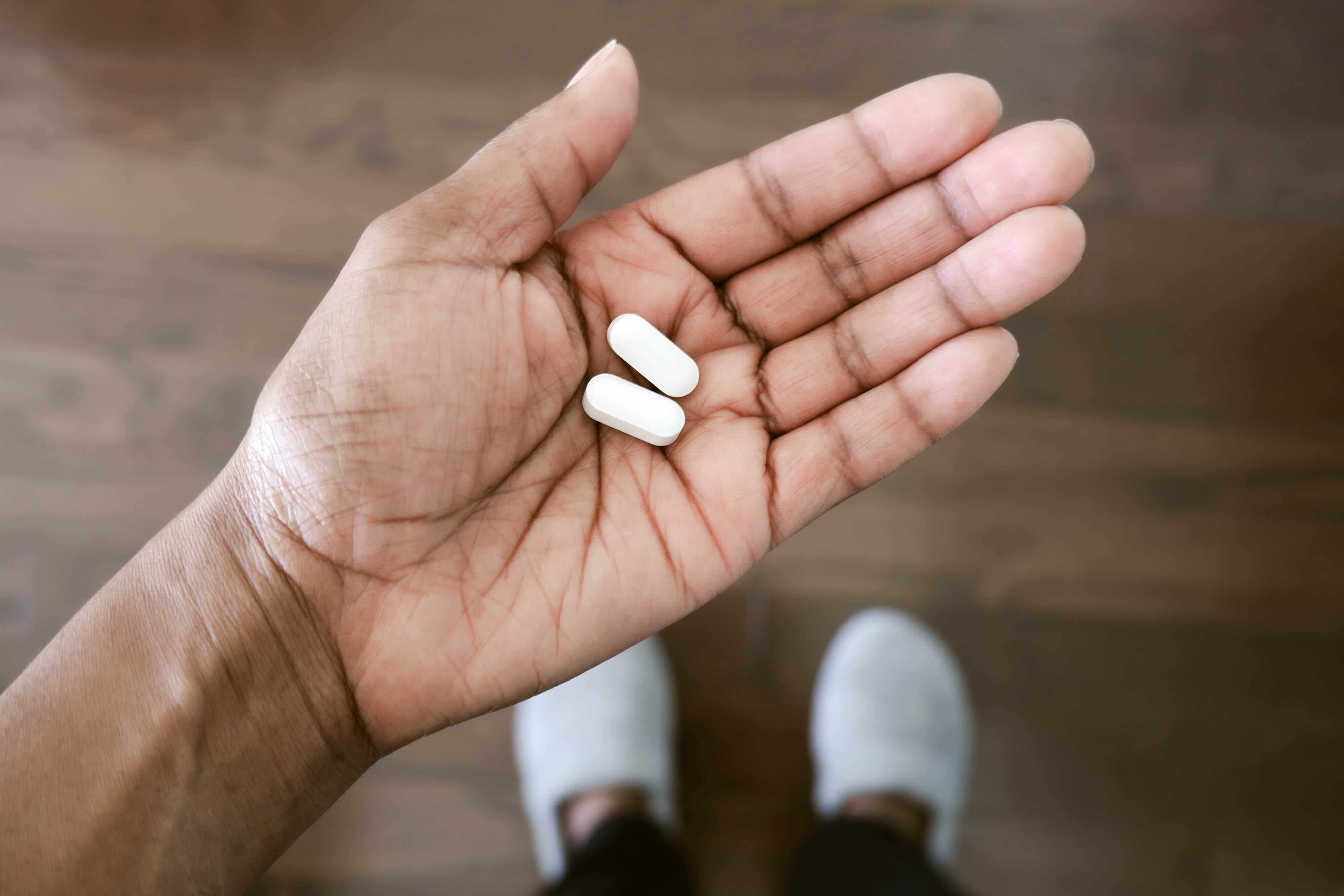 Close-up of unrecognizable black woman holding pills in palm of hand