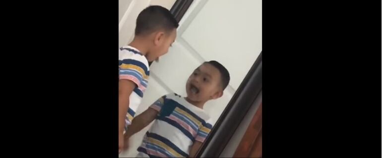 Niño se mira en el espejo y su reflejo es más rápido que él.