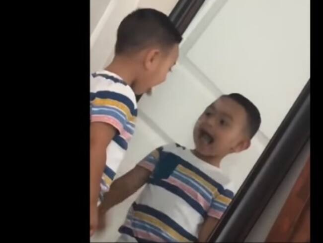 Niño se mira en el espejo y su reflejo es más rápido que él.