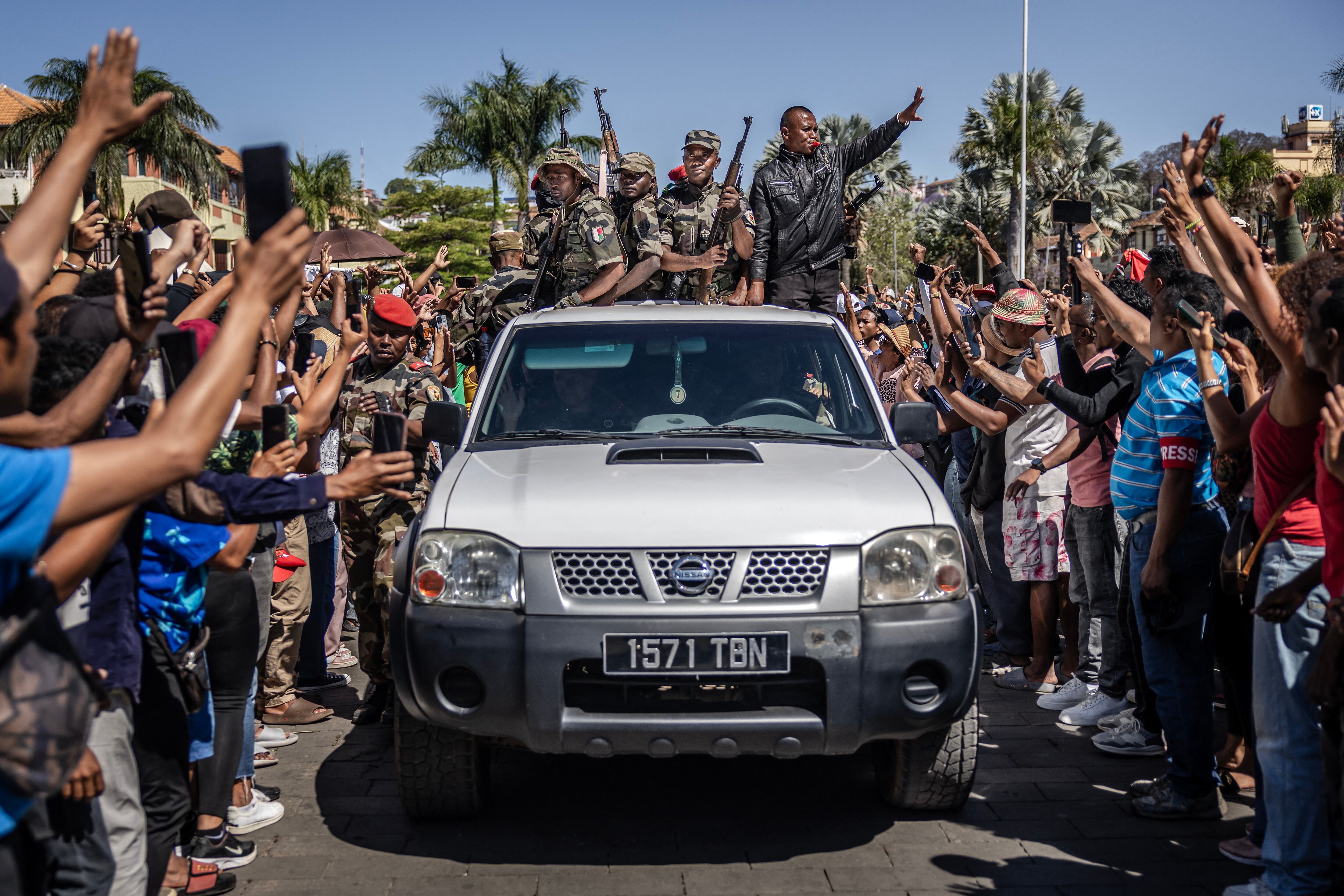 Members of Madagascar�s CAPSAT army unit patrol on a pickup truck as they are greeted with jubilation by residents gathered for ceremony honouring protesters killed in anti-government demonstrations in Antananarivo, on October 12, 2025. A mutinied army unit declared on October 12, 2025 that it was taking control of all Madagascar military forces as President Andry Rajoelina said an "attempt to seize power illegally" was under way.The CAPSAT contingent of administrative and technical officers joined thousands of protesters in the city centre on October 11, 2025 in a major shift in a more than two-week anti-government protest movement. (Photo by Luis TATO / AFP)