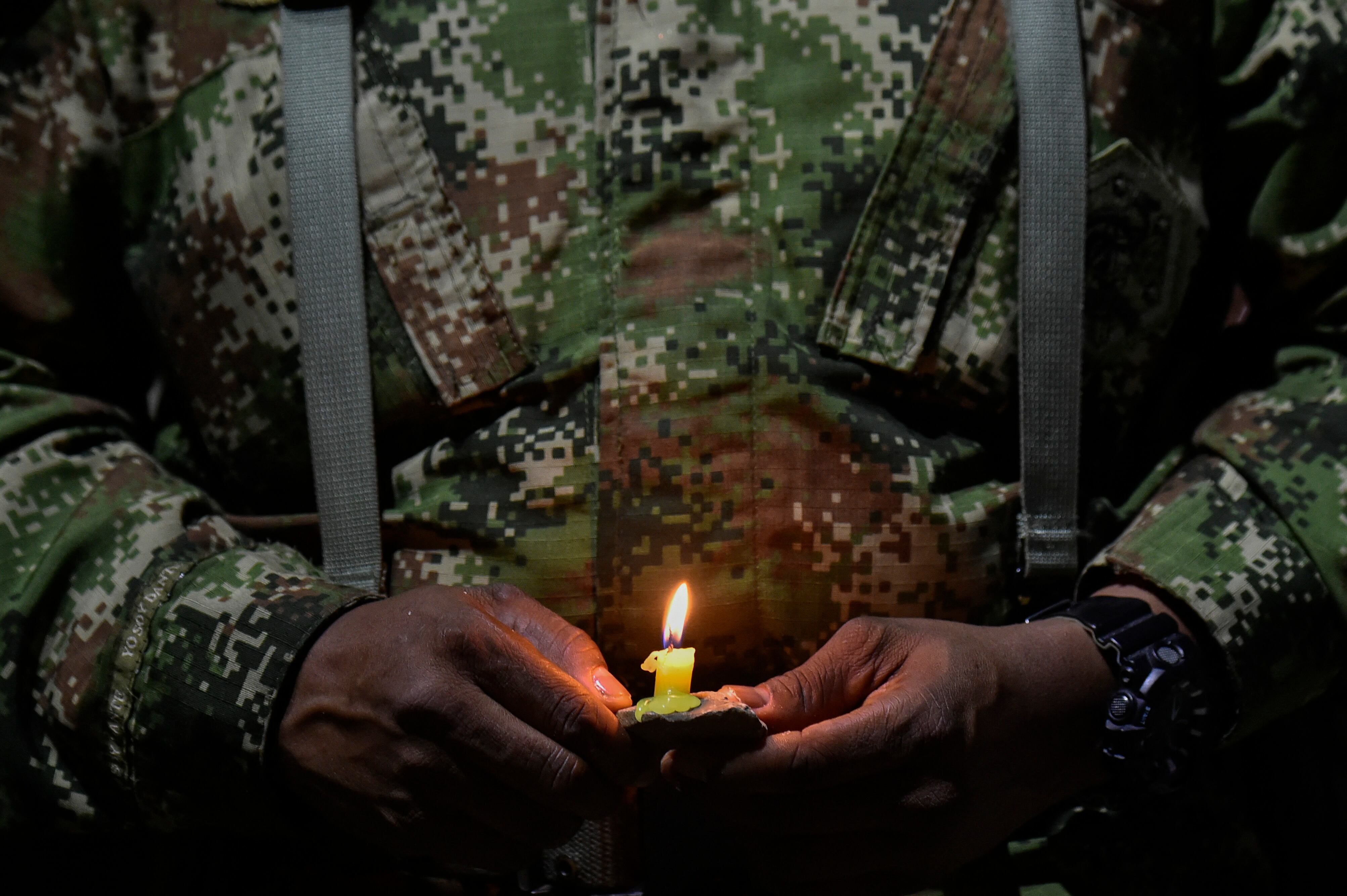 Un soldado colombiano enciende una vela durante un homenaje a los seis soldados que murieron tras un ataque de disidentes de las FARC. Foto de SCHNEYDER MENDOZA/AFP vía Getty Images.