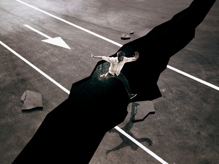 Hombre intentando saltar una grieta en el suelo- Gettyimages