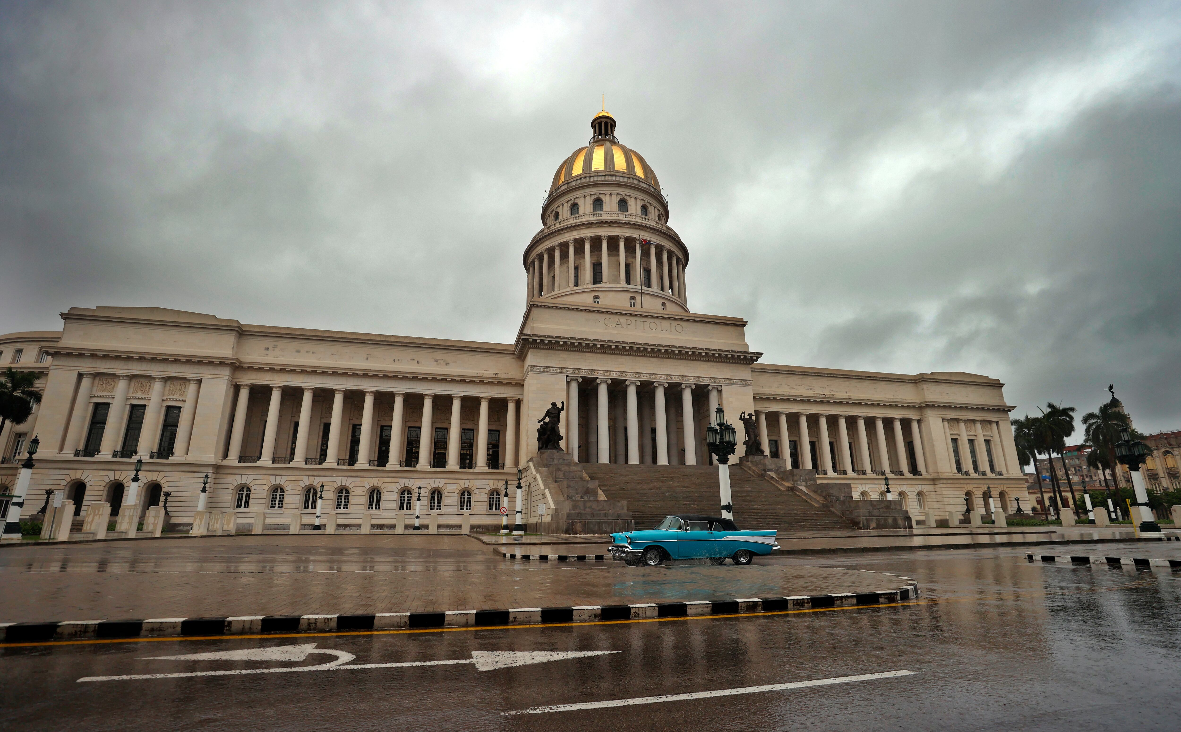 HAB01 LA HABANA (CUBA).- Una persona conduce hoy un vehículo bajo la lluvia, frente al Capitolio en La Habana (Cuba). El extremo occidental de Cuba espera este lunes en alerta el paso de la tormenta tropical Idalia, previsiblemente ya como huracán, con el recuerdo fresco de la devastación que ocasionó hace un año el ciclón Ian. Se prevé que el fenómeno provoque lluvias fuertes e intensas en el tercio occidental del país, lo que podría generar inundaciones rápidas, y que los vientos -hasta el momento sostenidos de hasta 75 kilómetros por hora- levanten marejadas fuertes que inunden zonas costeras bajas. EFE/Ernesto Mastrascusa