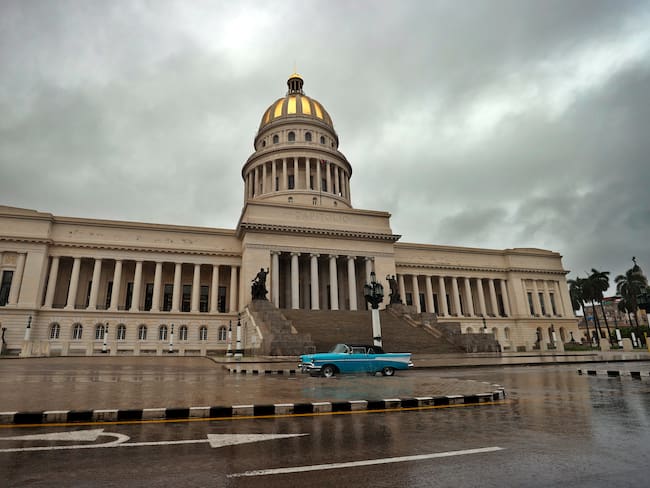 HAB01 LA HABANA (CUBA).- Una persona conduce hoy un vehículo bajo la lluvia, frente al Capitolio en La Habana (Cuba). El extremo occidental de Cuba espera este lunes en alerta el paso de la tormenta tropical Idalia, previsiblemente ya como huracán, con el recuerdo fresco de la devastación que ocasionó hace un año el ciclón Ian. Se prevé que el fenómeno provoque lluvias fuertes e intensas en el tercio occidental del país, lo que podría generar inundaciones rápidas, y que los vientos -hasta el momento sostenidos de hasta 75 kilómetros por hora- levanten marejadas fuertes que inunden zonas costeras bajas. EFE/Ernesto Mastrascusa