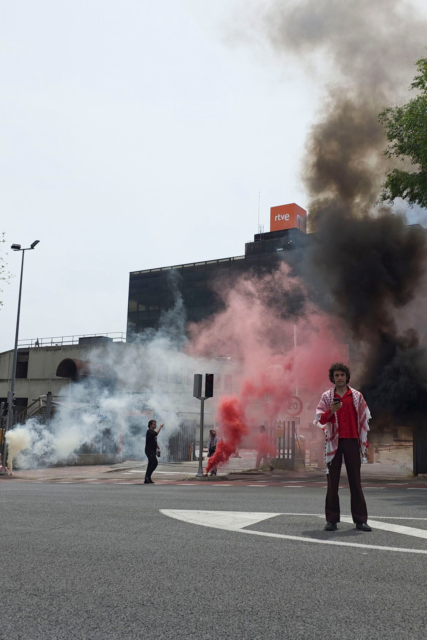 MADRID, 17/05/2025.- Miembros de la Acampada por Palestina de Madrid se han concentrado este sábado ante la sede de RTVE, en la calle Alcalde Sáinz de Baranda, para denunciar "el blanqueamiento mediante la música del genocidio israelí en Palestina" y para apoyar a trabajadores del ente público que "pueden ser censurados por señalar los crímenes de Israel". La protesta, que ha tenido lugar sobre las 15:00 horas, se desarrolló "de forma pacífica e incluyó el encendido de cuatro botes de humo" y la lectura de un comunicado de rechazo a la participación Israel en Eurovisión y "en apoyo de los locutores de TVE que durante la retransmisión de la semifinal hicieron comentarios sobre los muertos" causados por la ofensiva militar de Israel en Gaza. EFE/Acampada por Palestina de Madrid -SOLO USO EDITORIAL/SOLO DISPONIBLE PARA ILUSTRAR LA NOTICIA QUE ACOMPAÑA (CRÉDITO OBLIGATORIO)-
