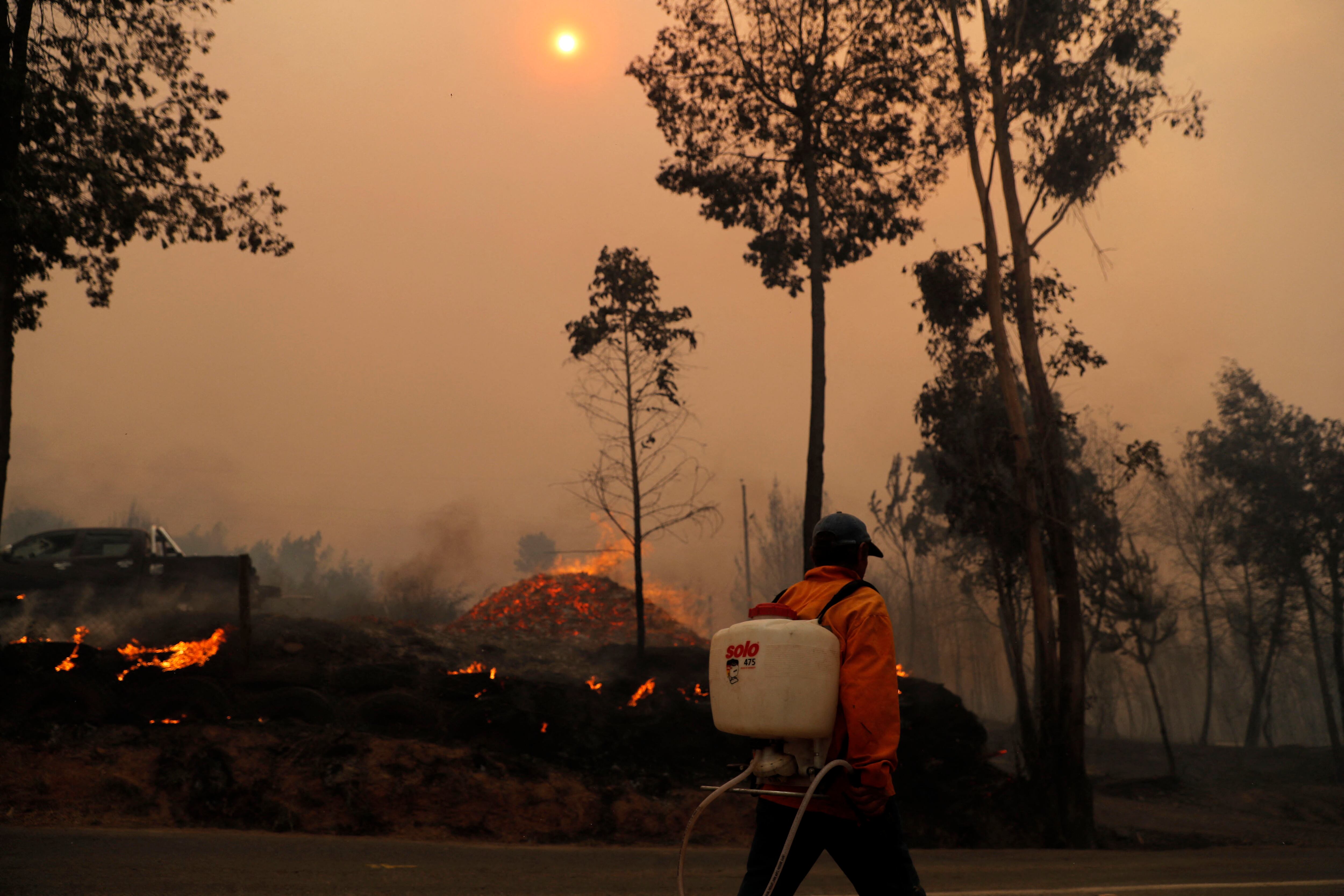 A man puts out a fire in Santa Juana, Concepcion province, Chile on February 3, 2023. - Chile has declared a state of disaster in several central-southern regions after a devastating heat wave provoked forest fires that left four people dead, authorities said on Friday. (Photo by JAVIER TORRES / AFP) (Photo by JAVIER TORRES/AFP via Getty Images)