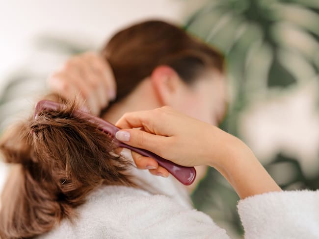 Mujer pasando un cepillo por su cabello (Foto vía Getty Images)
