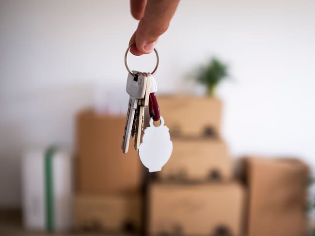 Close-up of the keys of the new empty apartment with moving boxes on the floor