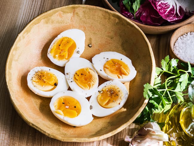Plato con algunos huevos partidos en dos junto a otros ingredientes de cocina (Getty Images)