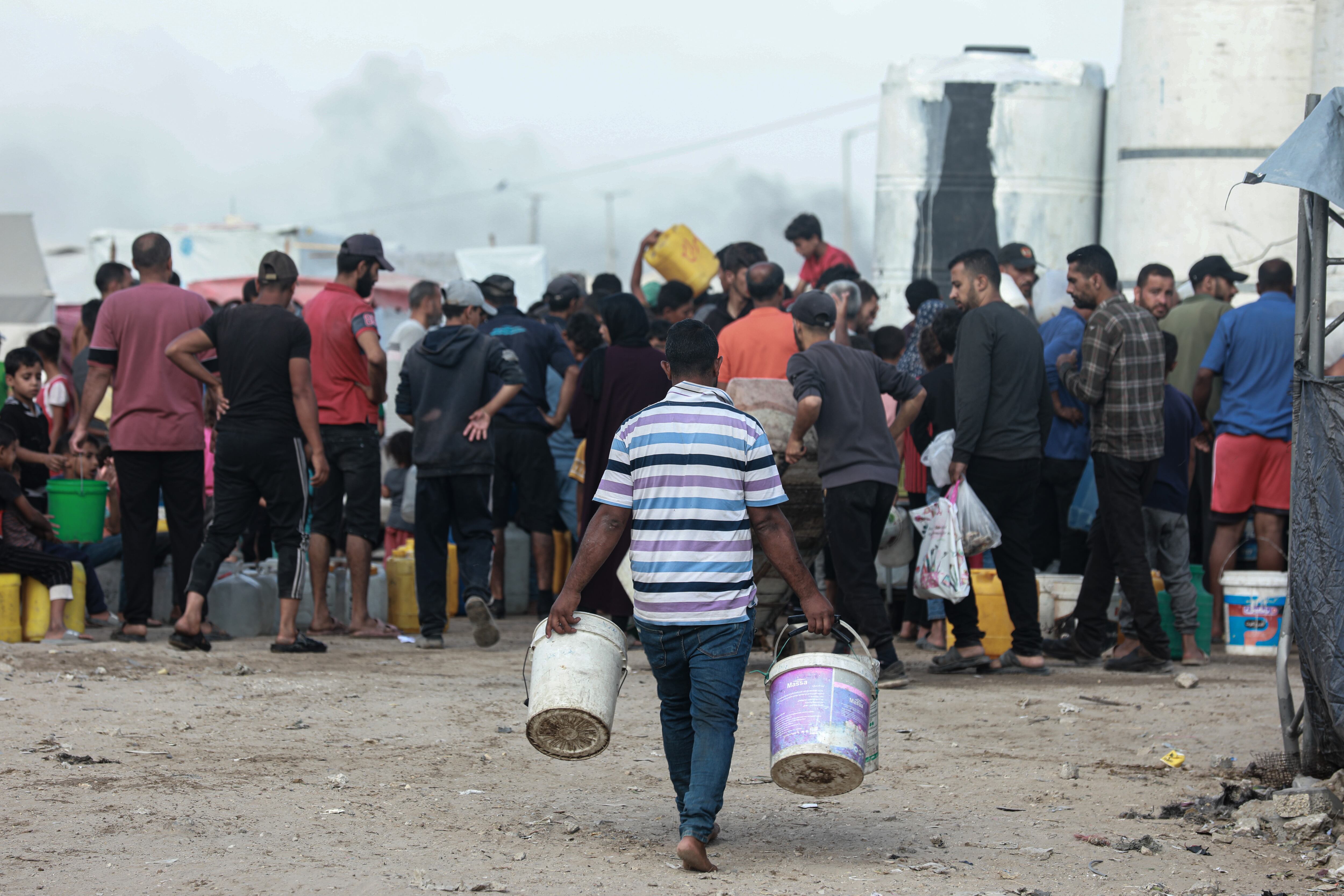GAZA CITY, GAZA - MAY 27: Palestinians, including children, fill and carry water distributed by a water tanker into containers in port area of Gaza City, Gaza on May 27, 2025. Due to ongoing Israeli attacks on Gaza and the closure of the borders, Palestinians are facing difficulties accessing water. (Photo by Abdalhkem Abu Riash/Anadolu via Getty Images)