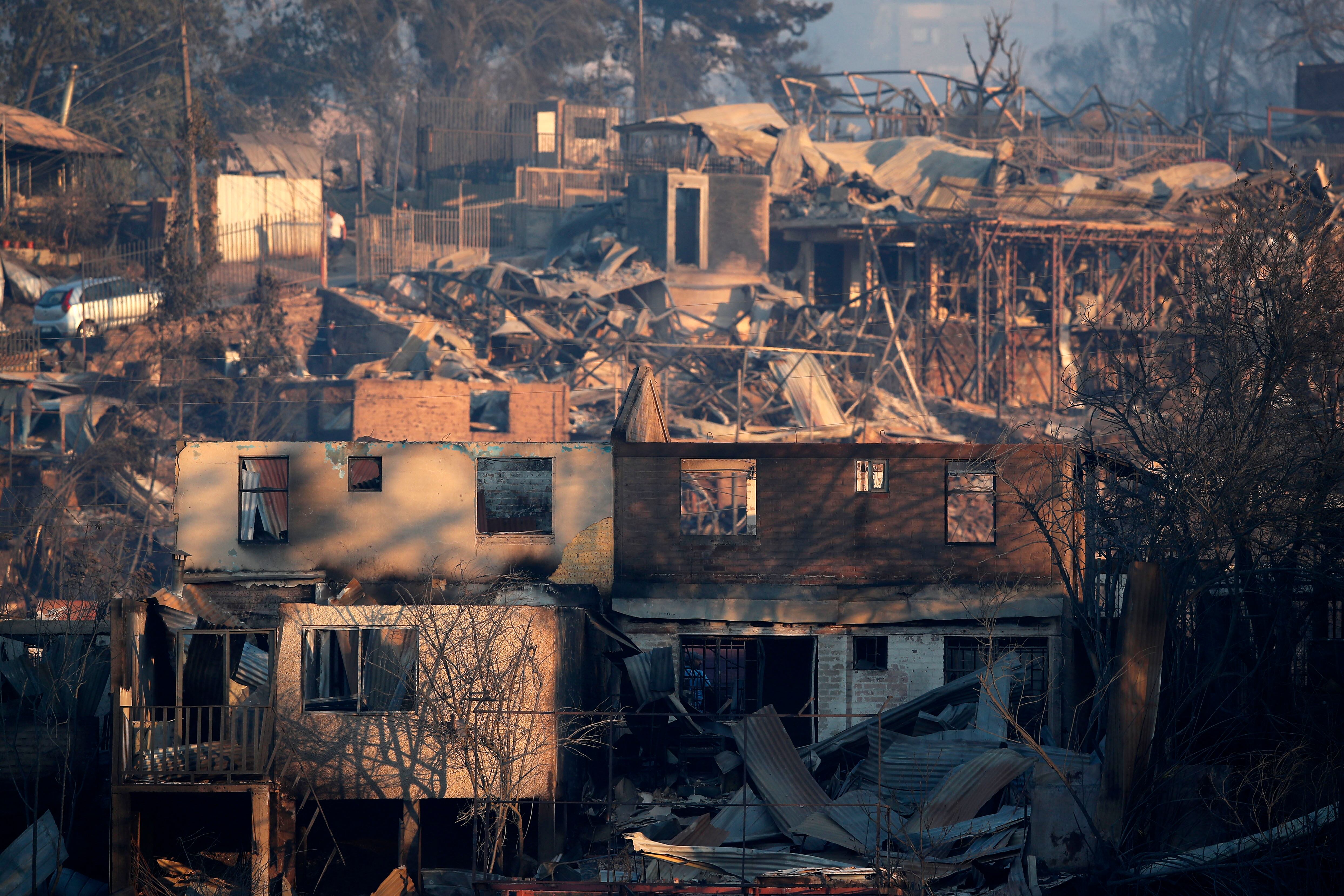 View of burnt houses after a fire that affected the hills in Vi�a del Mar, Chile on February 3, 2024. - The region of Valparaoso and Vi�a del Mar, in central Chile, woke up on Saturday with a partial curfew to allow the movement of evacuees and the transfer of emergency equipment in the midst of a series of unprecedented fires, authorities reported. (Photo by Javier TORRES / AFP)