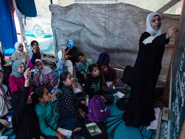 Khan Yunis (Gaza), 13/06/2024.- Estudiantes palestinos asisten a una clase en una escuela de campaña en el campo de refugiados de Khan Yunis, en el sur de la Franja de Gaza, este jueves. Después de que el ejército israelí destruyera escuelas en el sur de Gaza, un grupo de maestros palestinos estableció una &#039;escuela de campaña&#039; que incluye a 200 niños en edad escolar de 6 a 12 años en el campamento. Para los refugiados, el actual conflicto palestino-israelí ha privado a los estudiantes de sus estudios durante casi ocho meses. EFE/ Haitham Imad