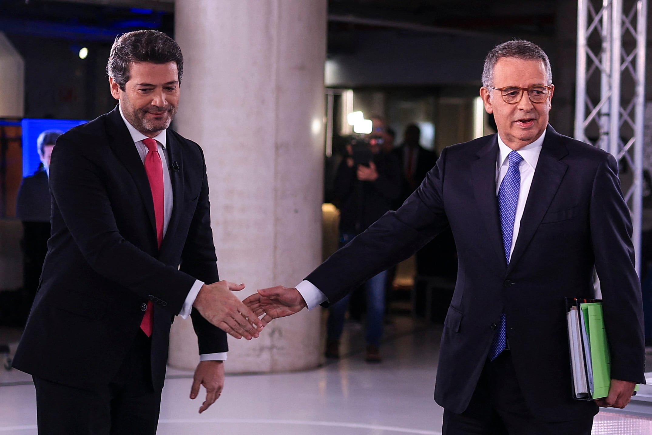 (FILES) Chega presidential candidate Andre Ventura (L) greets Socialist party candidate Jose Antonio Seguro at the start of a televised debate ahead of the February 8th Presidential election run-off, in Lisbon on January 27, 2026. Portugal on February 6, 2026 ended campaigning for a presidential election this weekend amidst a battering by storms and fretting about the political whirlwind created by outspoken far-right leader Andre Ventura. (Photo by PATRICIA DE MELO MOREIRA / AFP)