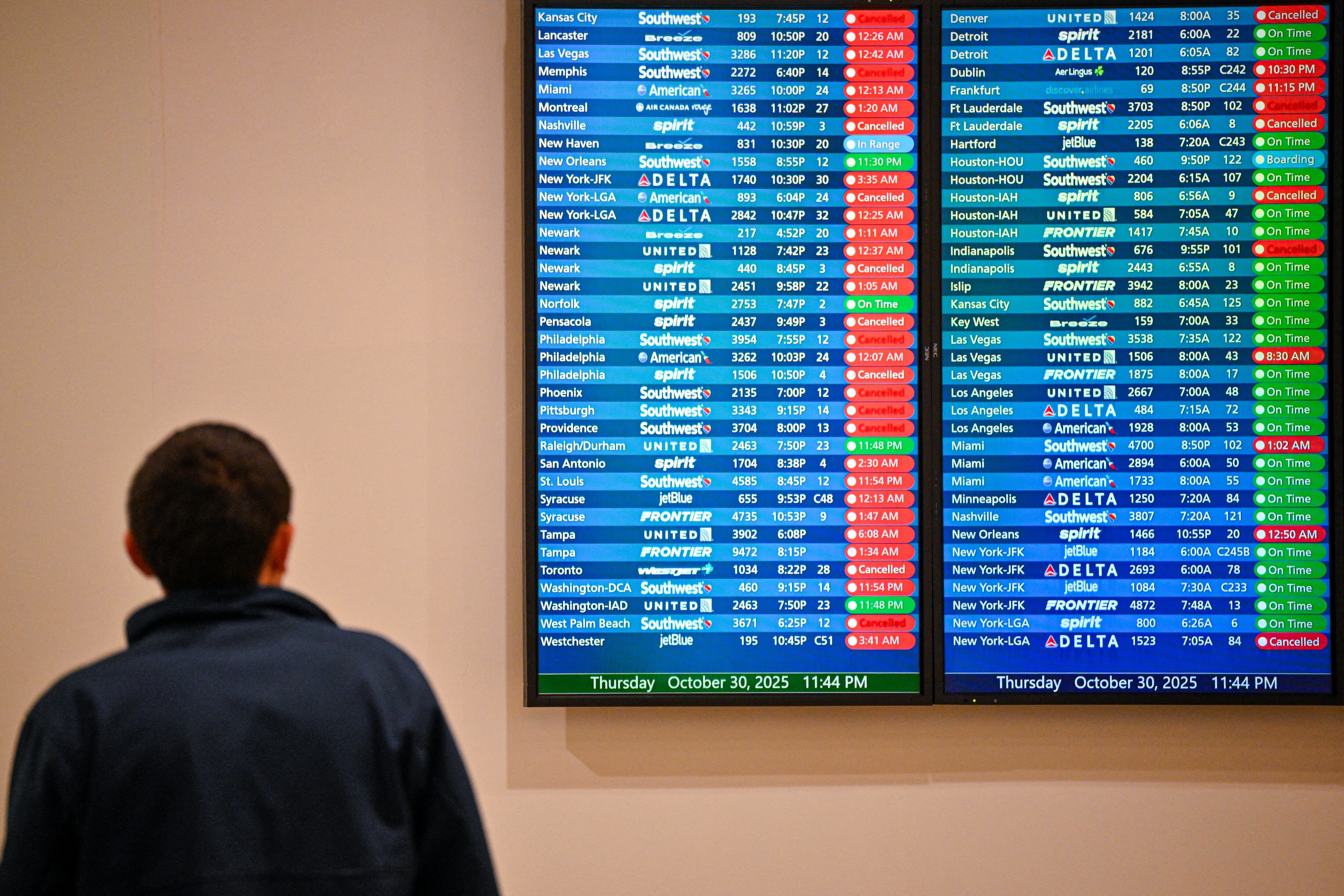 Cancelled flights are seen on a screen at Orlando International Airport in Orlando, Florida on October 30, 2025. Flights at Orlando International Airport faced major delays on October 30, after the Federal Aviation Administration (FAA) said the airport had no certified air-traffic controllers in its tower, forcing arrivals to be halted or severely delayed amid the ongoing US government shutdown.Air traffic controllers -- seen as "essential" public servants -- are kept at work during government shutdowns, but higher numbers are calling in sick rather than toiling without pay, leading to shortages. (Photo by Miguel J. Rodriguez Carrillo / AFP)