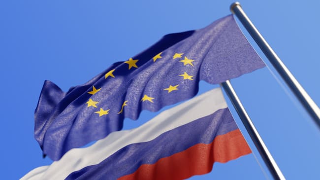 High quality 3d render of European Union and Russian flags waving with wind on a blue sky. Low angle view with copy space and selective focus.