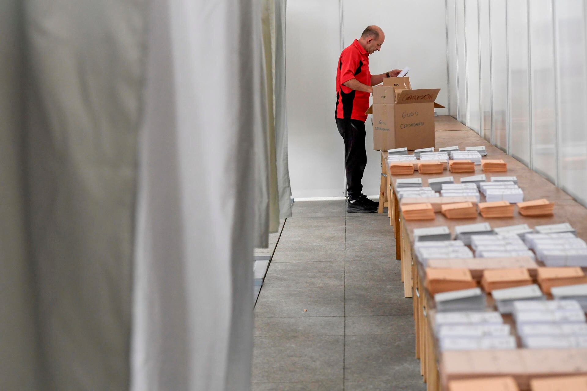 Operarios acaban de colocar y organizar este sábado, el material para el funcionamiento del colegio electoral para las votaciones con motivo de las elecciones generales de mañana, en Pola de Siero (Asturias). EFE/ Eloy Alonso