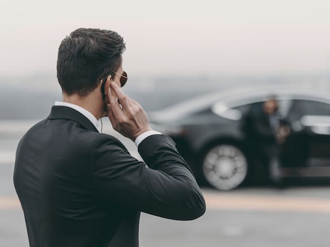 handsome bodyguard standing and listening message with security earpiece on helipad