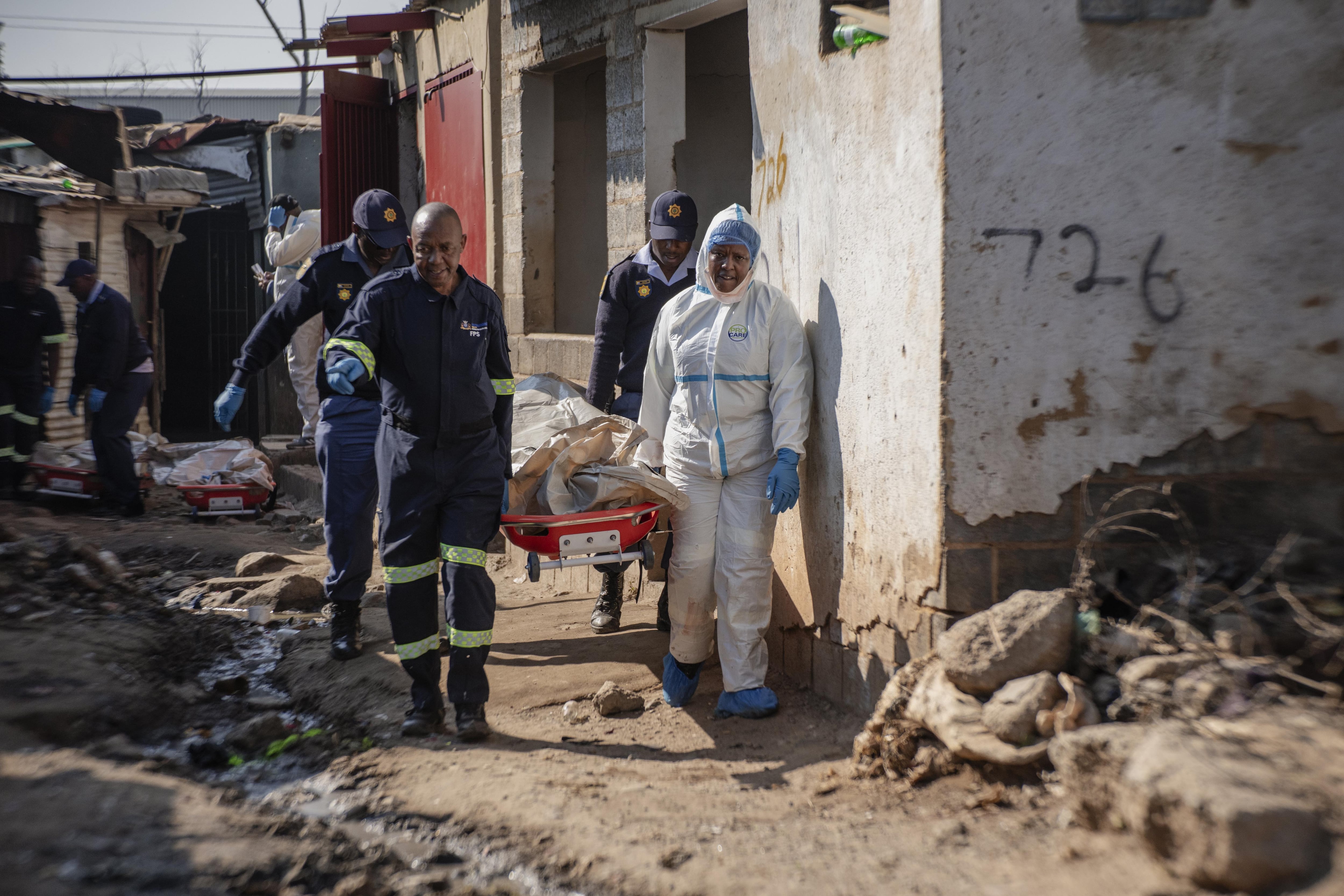 Oficiales mueven los cuerpos de los fallecidos en Johannesburgo, Sudáfrica (Photo by Ihsaan Haffejee/Anadolu via Getty Images)