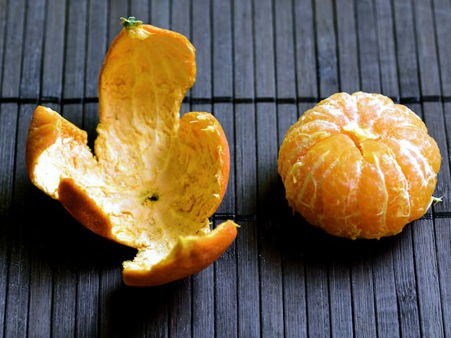 Peeled Mandarin Orange next to it's rind