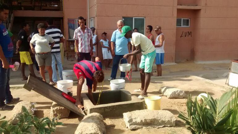 Los habitantes de Villas de la Cordialidad sacando agua de un tanque subterráneo