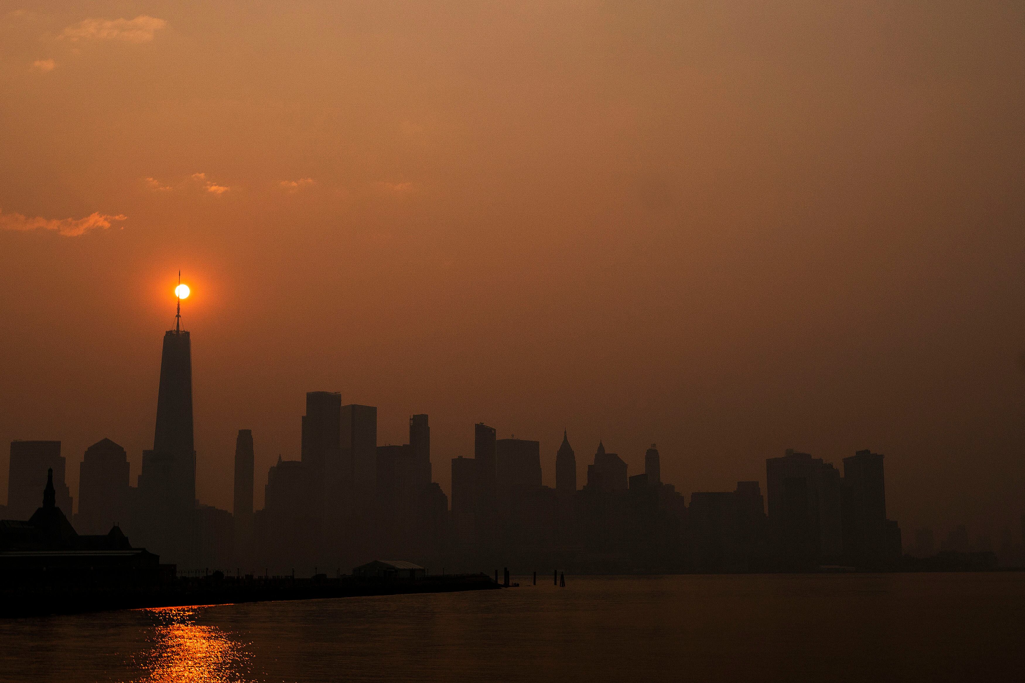 El sol sale detrás del One World Trade Center, mientras que el humo de los incendios forestales de Canadá cubre el distrito de Manhattan. (Foto de Eduardo Muñoz Álvarez/Getty Images)