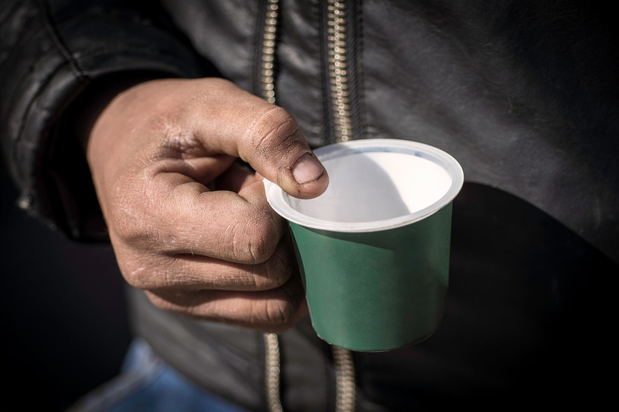 Dirty Beggar Hand Holding Plastic Cup. Poor Man Begging for Money on the Street Close Up.